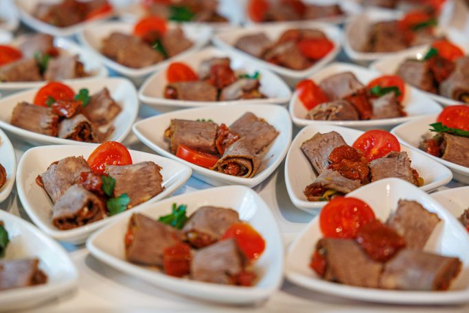 Verschiedene Teller mit Rinderroulade, Cherry-Tomaten und Petersilie.