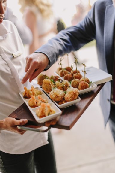 Firmenfeiern Vorspeisen auf einem Tablett, serviert von einer Person mit einem weißen Hemd.